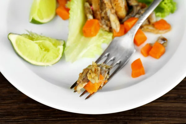 Fried small fish with carrot and greens on table close up — Stock Photo, Image