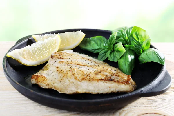 Plat de filet de poisson avec basilic et citron sur fond lumineux — Photo