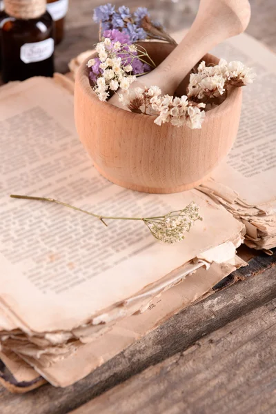 Stare książki z suchych kwiatów w moździerzu i butelek na stole z bliska — Zdjęcie stockowe