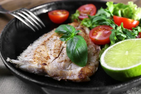 Dish of fish fillet with salad and lime on dripping pan close up — Stock Photo, Image