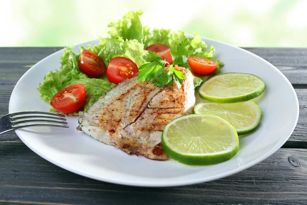 Plato de filete de pescado con ensalada y lima en la mesa de cerca — Foto de Stock