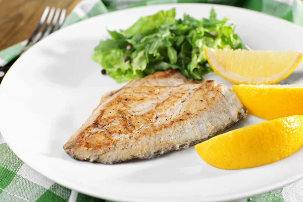 Maträtt av fiskfilé med gröna och citron på plattan på nära håll — Stockfoto