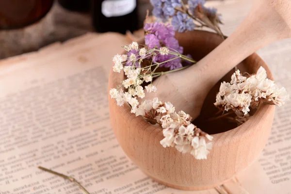 Livro velho com flores secas em argamassa e garrafas na mesa de perto — Fotografia de Stock