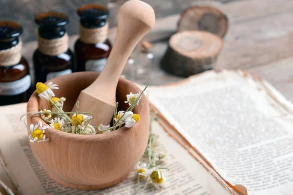 Old book with dry flowers in mortar and bottles on table close up — Stock Photo, Image