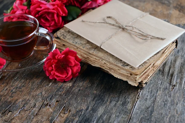 Oud boek met prachtige bloemen en een kopje thee op houten tafel close-up — Stockfoto