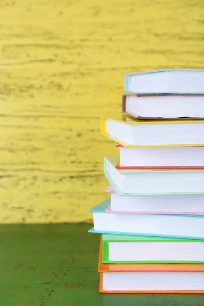 Sarı ahşap arka plan üzerinde kitap yığını — Stok fotoğraf