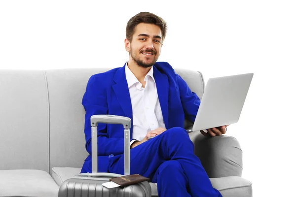 Homem de negócios com mala e laptop sentado no sofá isolado em branco — Fotografia de Stock