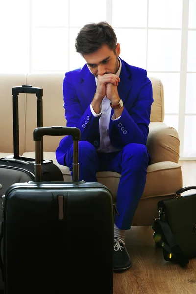 Деловой человек с чемоданами сидит на диване в холле — стоковое фото