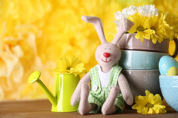 Paashaas met beschilderde Pasen eieren met bloemen op houten tafel op gele achtergrond — Stockfoto