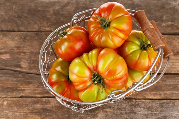 Groene tomaten in mand op houten achtergrond — Stockfoto