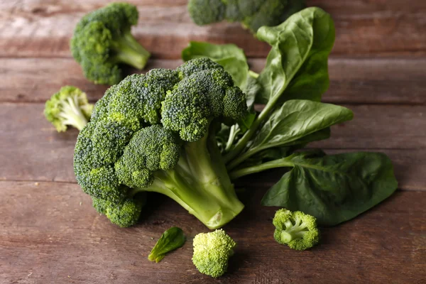 Fresh broccoli with spinach on wooden table close up — Stock Photo, Image
