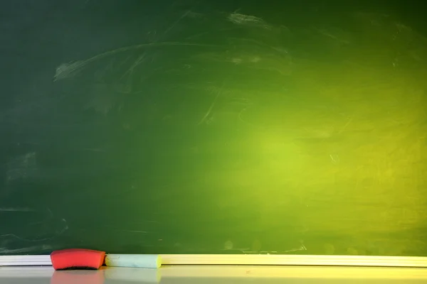 Blank blackboard with colored chalks and eraser. — Stock Photo, Image