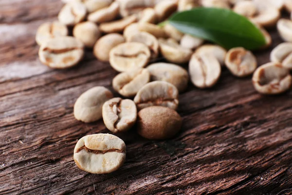 Hromadu zelené kávové boby na dřevěný stůl, detail — Stock fotografie