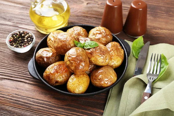 Patatas al horno en sartén sobre mesa de madera, primer plano —  Fotos de Stock