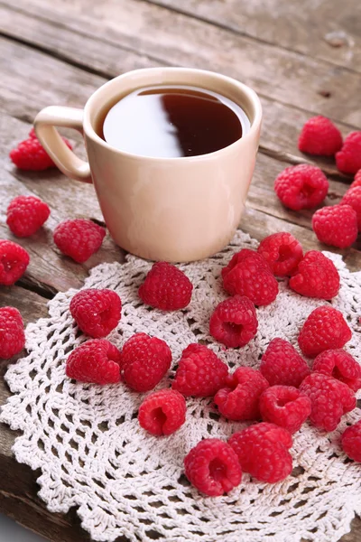 Fresh raspberries with cup of tea on wooden table with napkin, closeup — Stock Photo, Image