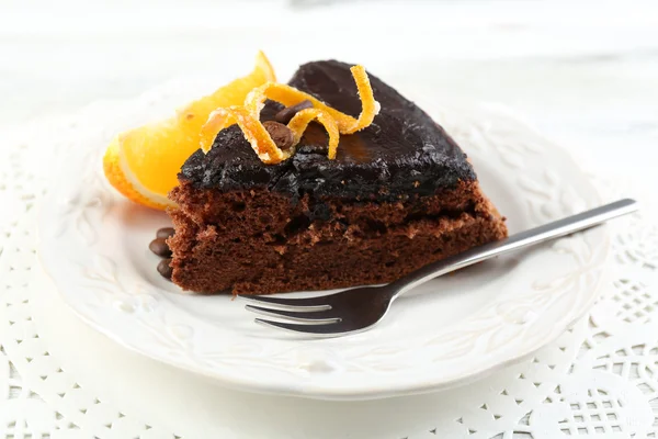 Piece of Chocolate cake and orange on plate, on table  background — Stock Photo, Image