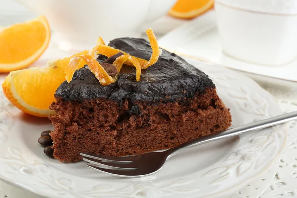 Pedaço de bolo de chocolate e laranja no prato, no fundo da mesa — Fotografia de Stock