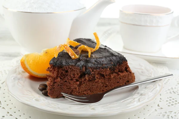 Piece of Chocolate cake and orange on plate, on table  background — Stock Photo, Image