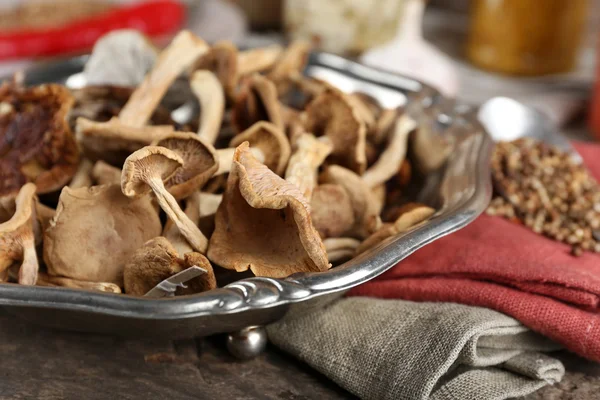 Dried mushrooms in metal tray with spices on wooden table, closeup — Stock Photo, Image