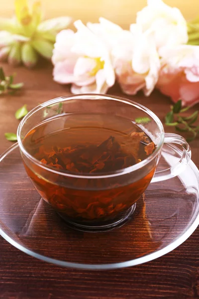 Чашка травяного чая с тюльпанами на деревянном столе, крупным планом — стоковое фото