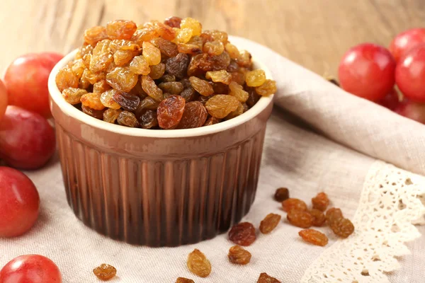 Raisins in bowl with grapes on table close up — Stock Photo, Image