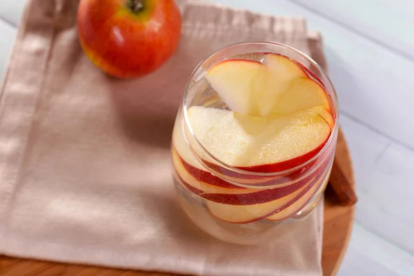 Glass of apple cider with fruits and cinnamon on table close up — Stock Photo, Image