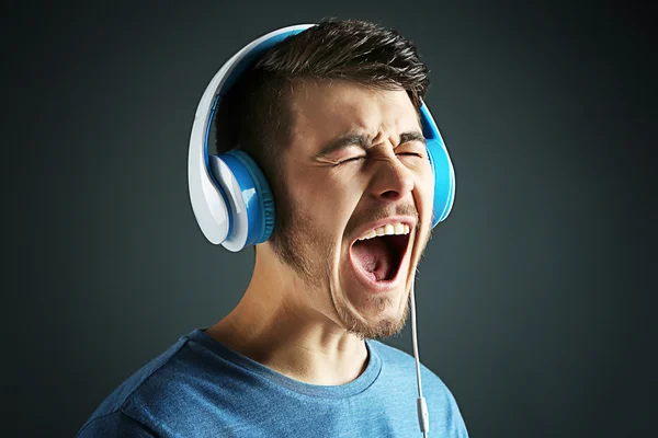 Handsome young man listening to music on  dark background — Stock Photo, Image