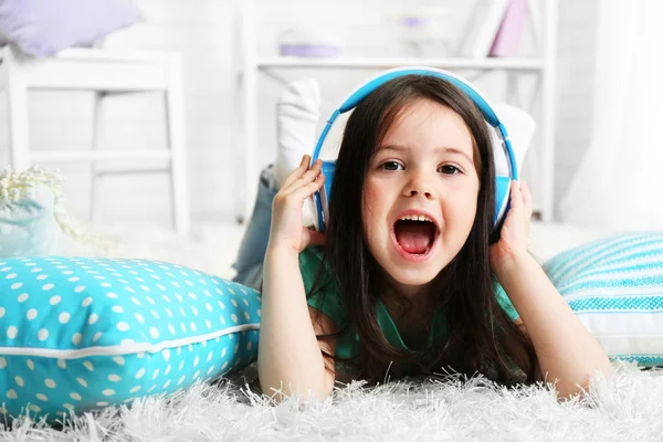 Beautiful little girl listening to music in room — Stock Photo, Image