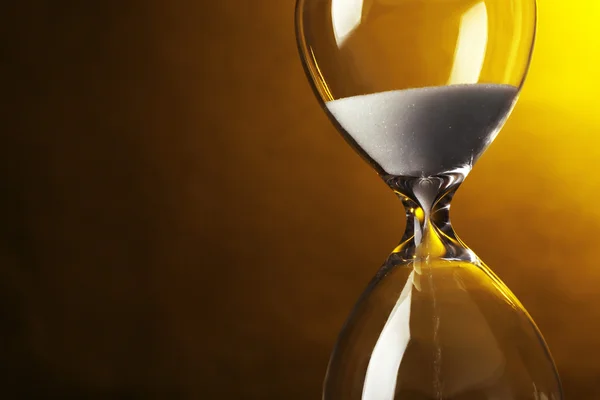 Hourglass on dark yellow background — Stock Photo, Image