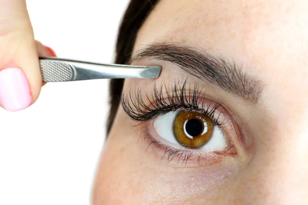 Young woman plucking eyebrows with tweezers close up — Stock Photo, Image