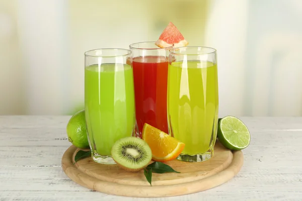 Стаканы различных соков с фруктами и мятой на ярком фоне — стоковое фото