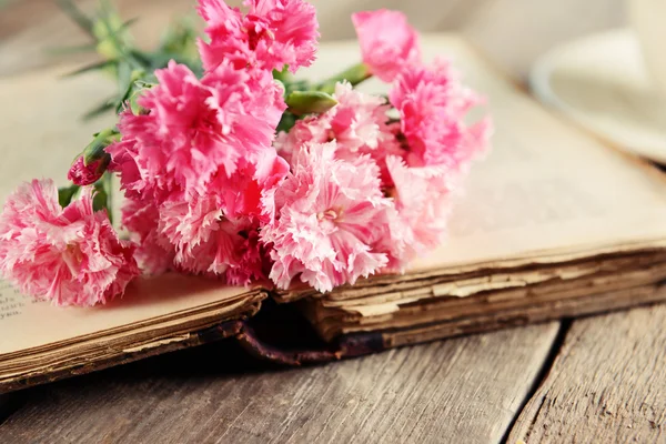 Gammal bok med vackra blommor på träbord nära håll — Stockfoto