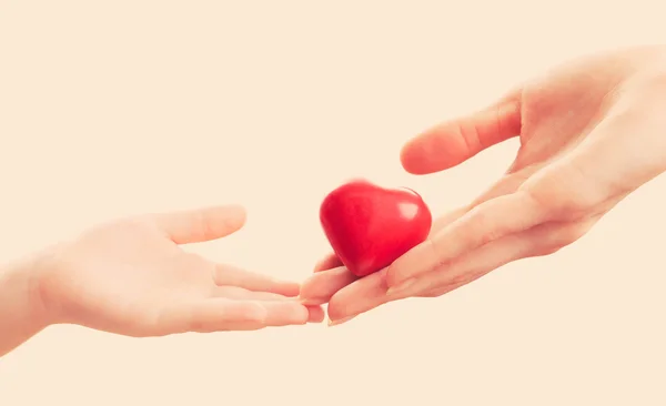 Herz in den Händen von Kind und Mutter auf hellem Hintergrund — Stockfoto