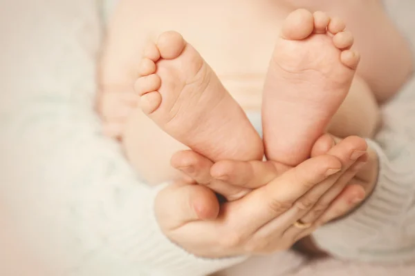 Newborn baby feet on female hands — Stock Photo, Image