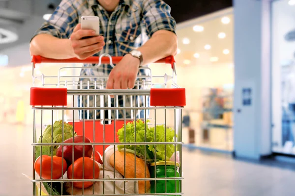 Young man with shopping cart in store — Stock Photo, Image