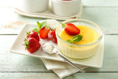 Creme brulee tatlısı peçeteye renk ahşap arka plan üzerinde taze çilek Çilek ile
