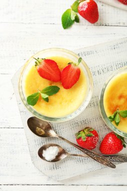 Creme brulee tatlı taze çilek ve renk ahşap zemin üzerine nane yaprakları ile