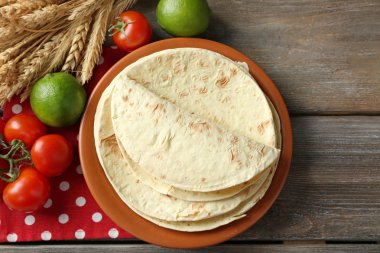 ev yapımı kepekli un tortilla ve ahşap masa arka plan üzerinde plaka üzerinde sebze yığını