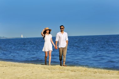 Genç bir çift sahilde yürüyor.