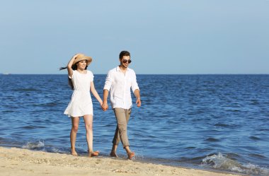 Genç bir çift sahilde yürüyor.