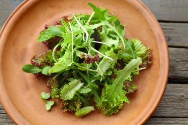 Ahşap masa üzerinde taze karışık yeşil salata tabak kapat