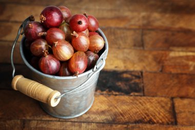 Ahşap arka plan üzerinde kova içinde yeşil bektaşi üzümü