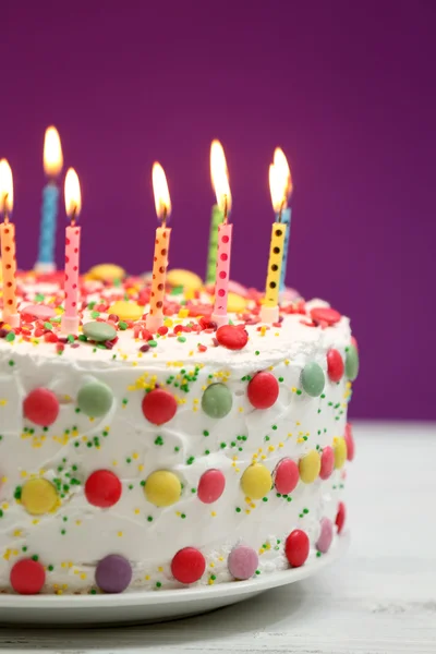 Verjaardagscake met kaarsen op paarse achtergrond — Stockfoto