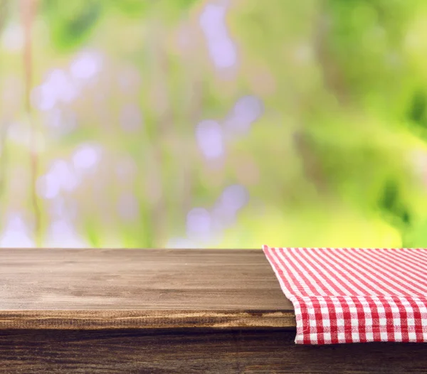 Mesa de madera vacía con servilleta sobre fondo brillante —  Fotos de Stock