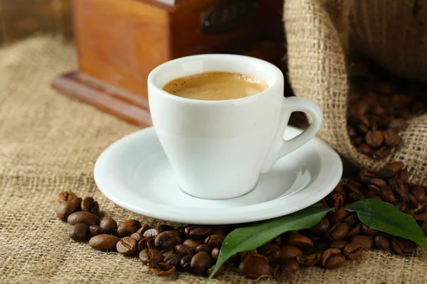 Cup of coffee with beans on table close up — Stock Photo, Image