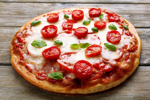 Смачна піца з сиром і вишневими помідорами на дерев'яному столі, крупним планом — стокове фото