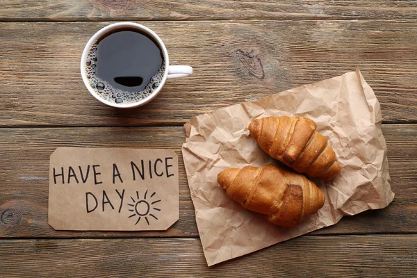 Taza de café con croissant fresco y tener un buen día de masaje en la mesa de madera, vista superior — Foto de Stock