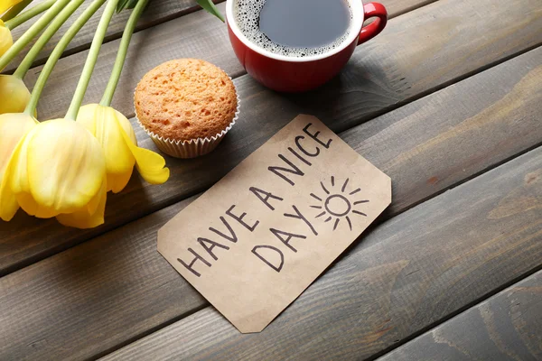 Tasse de café avec cupcake frais, tulipes et avoir une belle journée massage sur fond de bois — Photo