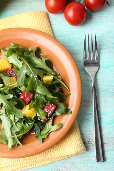 Вкусный салат с листьями рукколы в тарелке на деревянном столе, крупным планом — стоковое фото