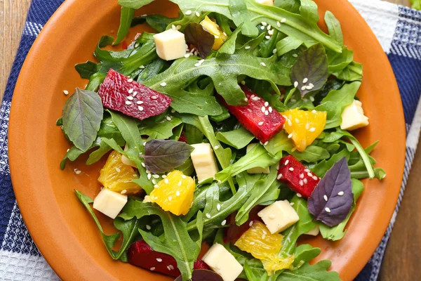 Salade savoureuse aux feuilles de roquette dans une assiette sur une table en bois, gros plan — Photo